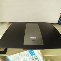 Front top view of Linksys EA6500 router showing black body with gray central panel and Linksys branding.