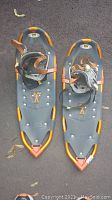Gray and orange TSL snowshoes on asphalt