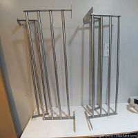 Two stainless steel towel racks with brushed nickel finish displayed upright against a wall on a white surface. Each rack has multiple parallel bars spaced vertically and measures approximately 31.5 inches in width. The racks show no visible damage and appear lightly used.