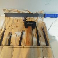 Woodworking tools including heavy mallet, chisels, and file on canvas pouch