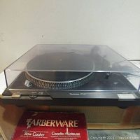 Front view of Technics turntable with clear hinged dust cover in place