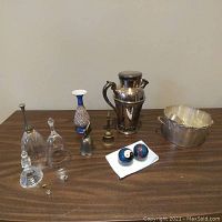 Group photo of all items on wooden surface showing silver shaker, ice bucket, bells, vase, glass bells, and small miscellaneous items.