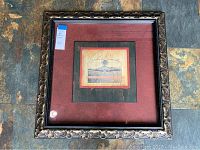 Framed wall art in a decorative floral carved dark wood frame with red matte background, showing whole piece.