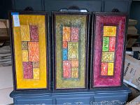 Three framed textured canvas wall art pieces hanging side by side, showing overall set and color coordination.