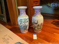 Front view of two Chinese porcelain vases showing nature paintings and decorative patterns.