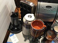 Photo showing the coffee maker, grinder, Mikasa carafe and stacked mugs in metal holder along with black K cup holder.