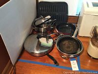 Photo of pots and pans with lids and broiler pan showing inventory and condition