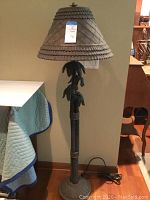 Full view of the 59-inch tall outdoor floor lamp with palm tree motif base and textured decorative shade.
