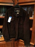 Front view of brown suede leather jacket on hanger showing buttons and collar.