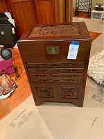 Front view of the Asian silverware chest showing carved wooden top, drawers, and cabinet doors with brass latch.