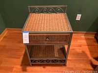 Full view of wicker side table showing metal frame, wicker top, drawer, and decorative scrollwork
