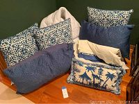 Blue and white Asian-designed pillows, blue queen shams, and pagoda throw pillow arranged on floor to show design and colors