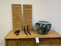 Photo showing two bamboo shelf planks, two black metal brackets with mounting screws, and a round ceramic planter on a wood surface.