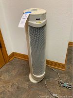 Front view of Bionaire oscillating air filter showing perforated metal mesh for air intake, control panel on top, standing on floor.