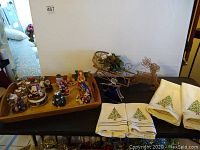 View of assortment including multiple Santa music boxes, stained glass style angel, wireframe gold reindeer with sleigh, and holiday towels.