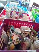 Basket containing various ceramics including figurines, pitchers, containers, and planters