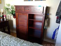 Front of Panama Jack tall wooden dresser with three top drawers, louvered door on left, and shelving on right