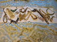 Full layout of assorted necklaces and bracelets on a textile surface showing about a dozen pieces with mixed designs including pearl, chain link, turquoise stone, and metallic elements.