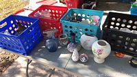 Multiple flower pots and holders in crates and on a table, varying shapes and sizes
