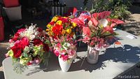 Photo showing all five floral arrangements grouped on a table in sunlight.