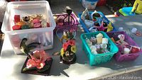 Overview of six boxes and baskets with assorted candles, candle holders, and decorative items on a table outdoors.