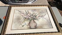 Front view of large floral print in vase with muted pastel colors, triple matted and gold wood frame, photographed in daylight.