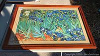 Frontal image of the framed floral print showing the hardwood frame with some scratches and the colorful floral artwork.
