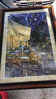 Full front view of framed abstract print depicting an outdoor cafe scene at night with empty tables and chairs.