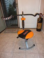 Front view of AbDoer Twist exercise machine showing padded black and orange seat and central twisting mechanism with foam padded handles.