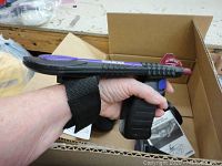 Laser tag gun held in hand showing side view with strap and trigger