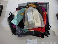 Stack of assorted shiny gift bags in various colors and sizes showing textures and drawstring details