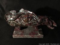 Side view of raku finish ceramic sculpture showing abstract flowing form and carved patterns on marble base.