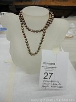Full view of the cocoa pearl necklace displayed on a bust form, showing the length and drape of the strand.