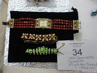 Lot showing the watch, flower brooch, and green rhinestone caterpillar pin displayed on a black pouch with identification note.