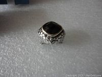 Front view of the ring showing the black onyx stone, silver textured band, and gold trim around the stone.