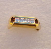 Close-up photo of ring face showing four square cut cubic zirconia stones set in triple plated 14K gold band.