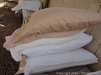 Stack of pillows showing 3 standard pillows with beige and white cases.