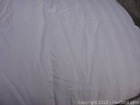 White queen size goose down comforter with smooth and lightly wrinkled texture, shown close-up.