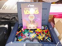 Open carrying case showing instruction book titled 'Book of Big Ideas' and assorted K'NEX pieces inside.