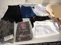 Assorted women's clothing items laid out including Capri pants, shorts, and packaged new items.
