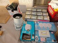 Photo showing assorted boxed LED and compact fluorescent bulbs, plus tray of round bulbs and one single LED bulb package