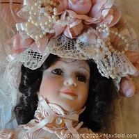 Close-up of doll's face showing brown hair, brown eyes with eyelashes, bonnet decorated with pink roses, lace, and pearls