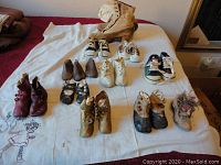 Full group shot of various antique baby shoes, vintage sneakers, wooden shoe lasts and women's shoes on a white cloth