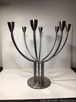 Front view of the 8-arm stainless steel candelabra showing the smooth brushed finish and eight tubular curved arms with candle holders.