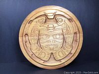 Front view of round bent wood box with carved Native American motifs.