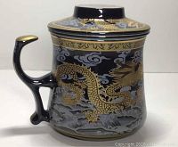 Side view of the black porcelain mug showing gold gilt dragon and cloud motif with gold tipped handle
