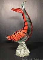 Front view of the Murano Sommerso glass koi fish sculpture on clear textured pedestal base, showing vibrant red, black, and green glass layers.