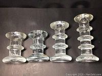 Front view of four vintage Iittala Festivo glass candle holders showing different heights and textured ring design