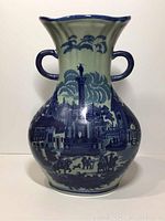 Front view of antique blue and white Staffordshire vase with cityscape design and two handles, marked Victoria Ware.