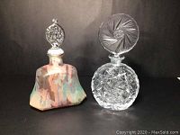 Two perfume bottles displayed side by side on a black background, showing frosted multi-coloured bottle and clear pinwheel cut crystal bottle with stoppers, highlighting their shapes and condition.